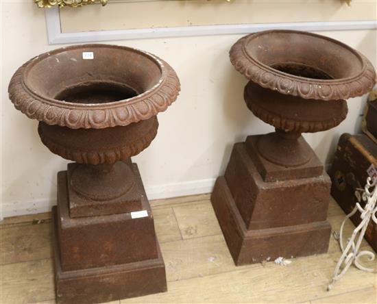 A pair of cast iron urns and pedestals, W.50cm